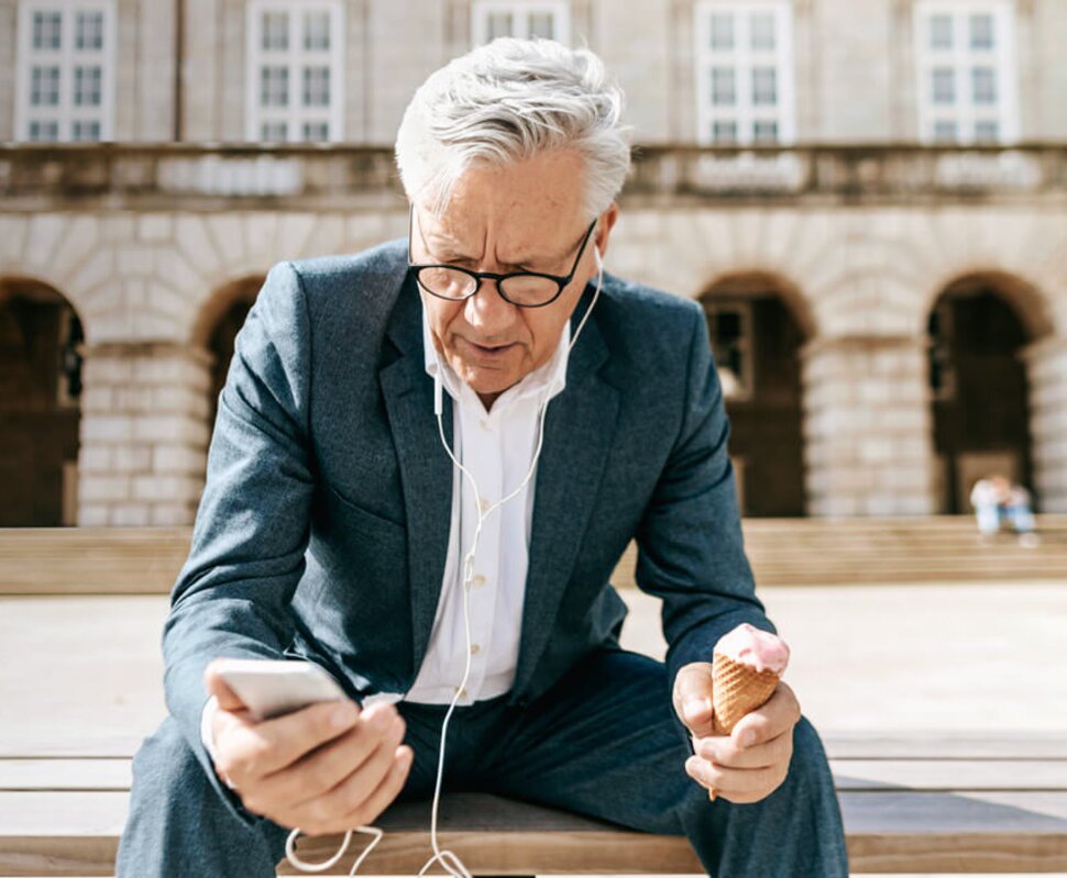 Junge Frau sitzt am Tisch, schreibt auf einer Versandbox und arbeitet mit einem Laptop in einem kreativ gestalteten Raum.