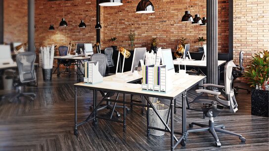 Modernes Büro mit mehreren Arbeitsplätzen, Holz- und Metallmöbeln, Pflanzen und einer ziegelsteinernen Wand.