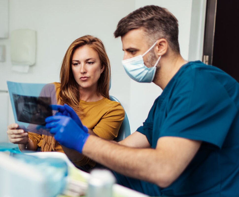 Zahnmedizinische Beratung: Ein Arzt und eine Patientin betrachten gemeinsam eine Röntgenaufnahme in einer modernen Praxis.