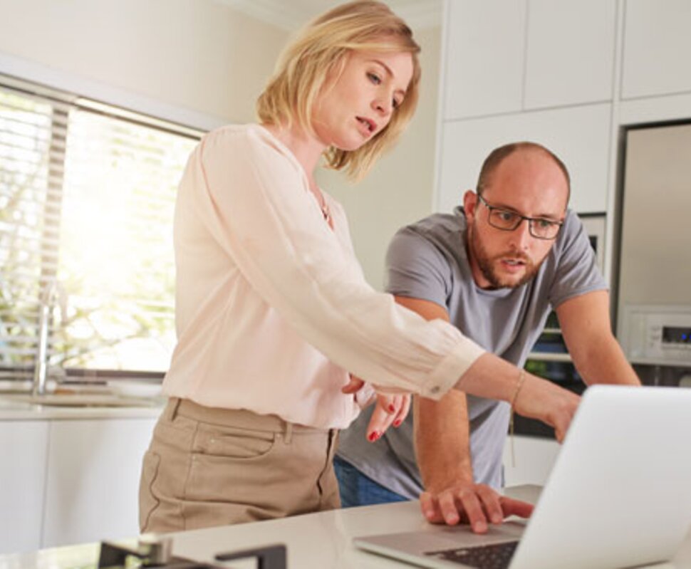 KI-generiertes Bild: Ein Mann und eine Frau stehen in einer modernen Küche und betrachten gemeinsam den Bildschirm eines Laptops.