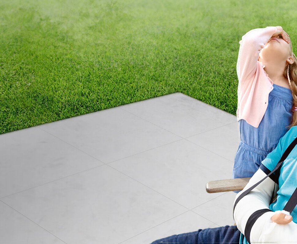 Lächelnder Mann mit Hals- und Armverband, der mit einem Kind im Hintergrund, das den Kopf zurückwirft, ein Selfie macht.