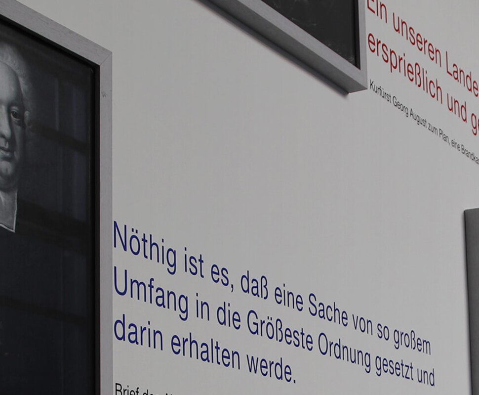 Porträts historischer Persönlichkeiten mit informativen Texten und Zitaten auf einer ausstellungsähnlichen Wand.